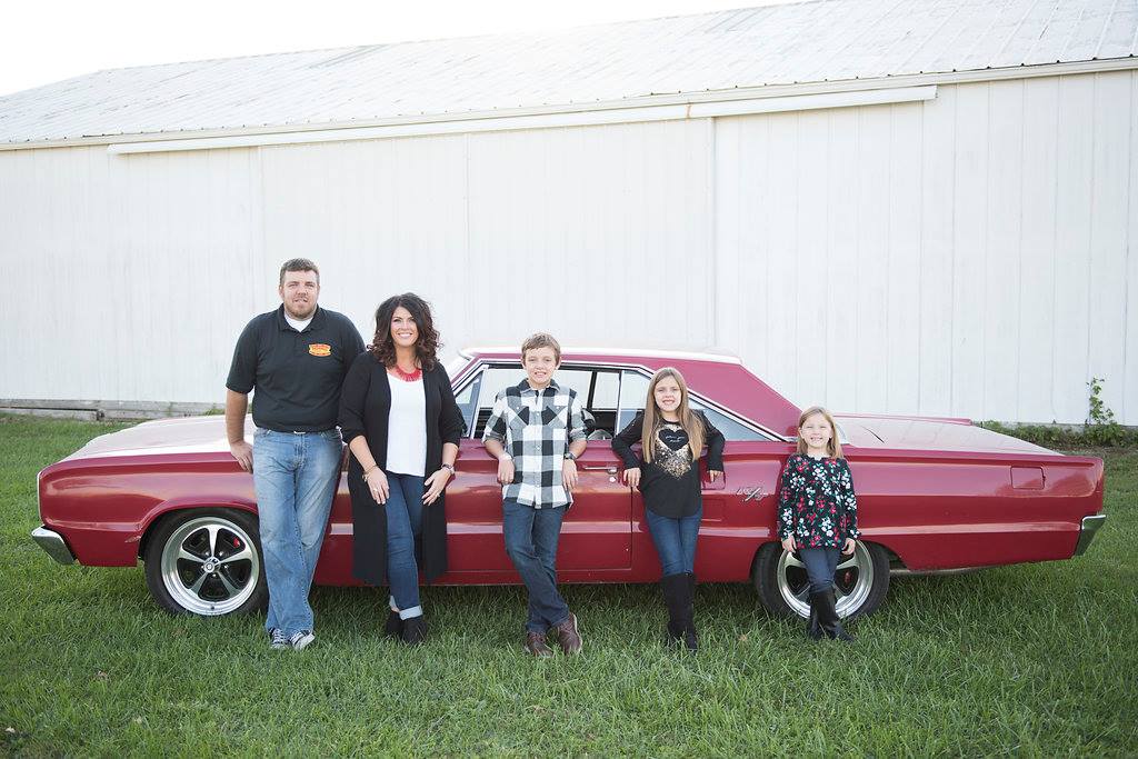 Morris Mopars family posed in front of classic red muscle car
